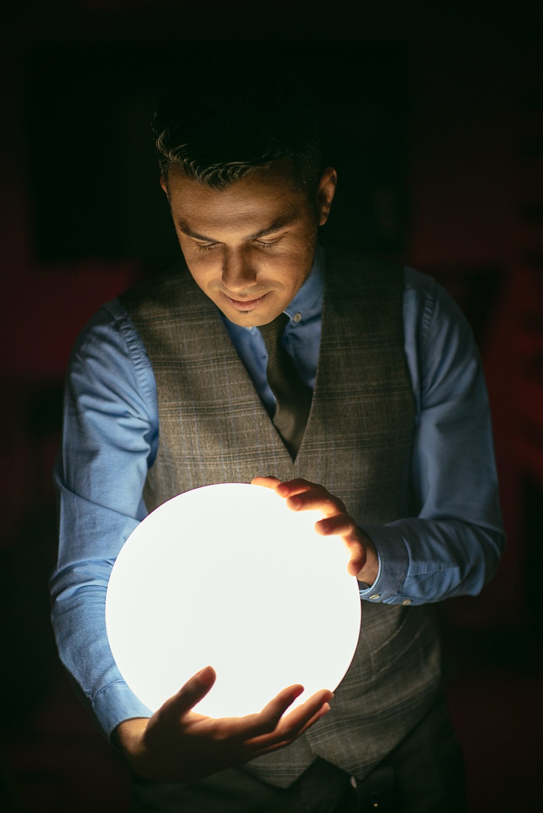 Hussain Alarab looking down at a glowing sphere held in his hands