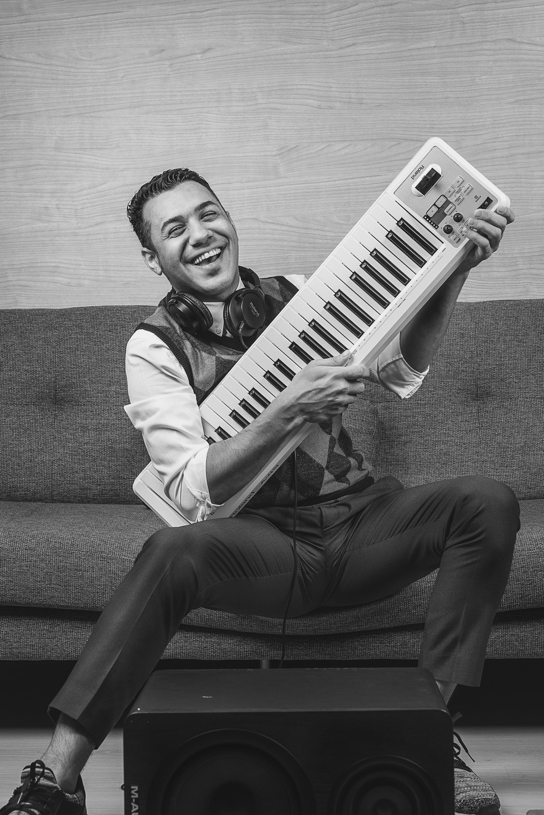 Black-and-white portrait of Hussain Alarab laughing while holding a keyboard